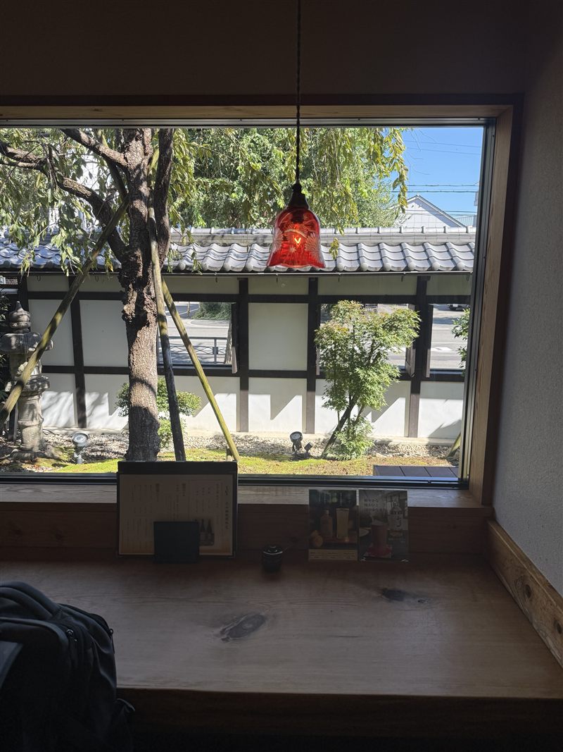 窓辺の席から見える庭と白い塀